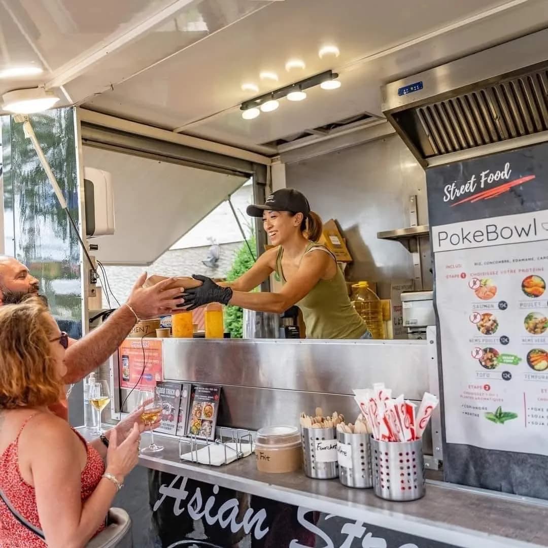 Carmen sert un repas asiatique depuis le food truck, en prestation entreprise devant les équipes